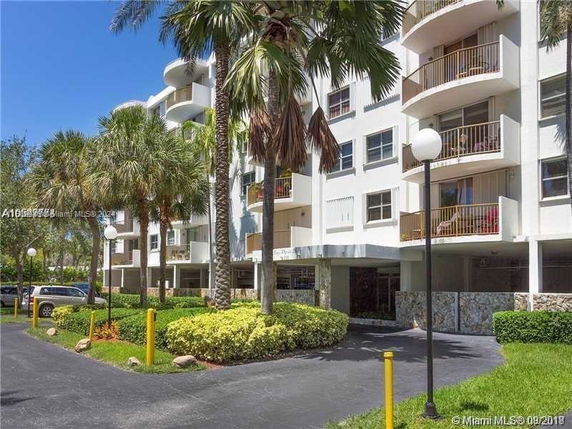Front view of a multi-story residential building with balconies and palm trees.