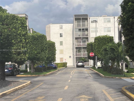 Front view of a multi-story apartment building with a parking area.