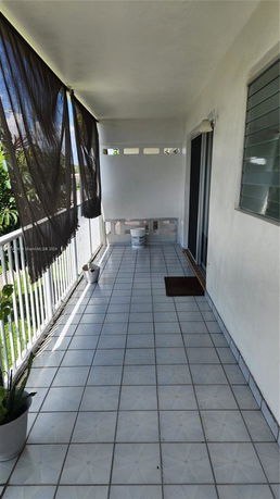 Outdoor view of a balcony with tiled floor and white railing.