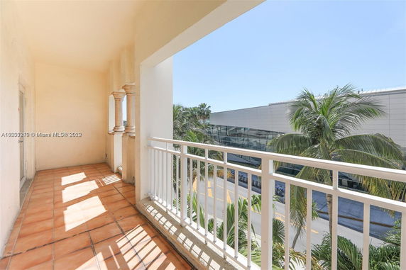 Balcony view from a building overlooking a modern structure and palm trees.