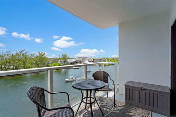 Balcony view overlooking a body of water with boats and surrounding greenery.
