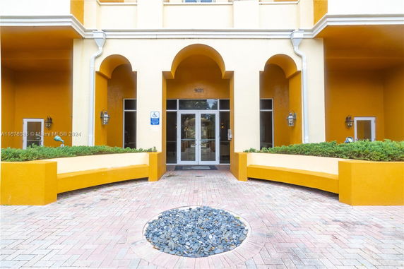 Front view of a building entrance with large arches and glass doors.