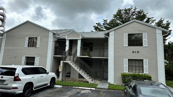Front view of a two-story residential building with stair access and visible parking area.