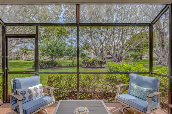 Screened patio area with chairs overlooking a landscaped garden and trees.