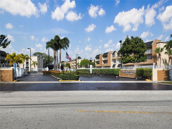Front view of a multi-story condominium complex with a gated entrance.
