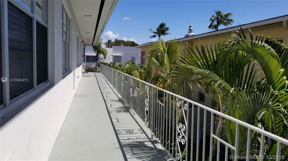Exterior corridor with railing and view of adjacent building.