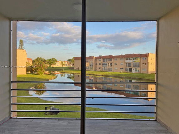 Panoramic view from a balcony showing apartment buildings and a pond.