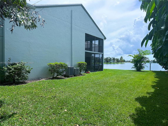 Side view of a building with a screened porch and a lake in the background.