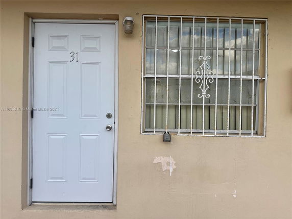 Front view of a house with a white door and barred window.