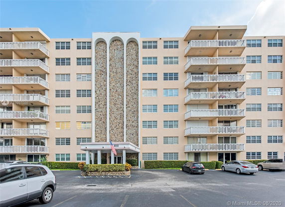 Front view of a multi-story building with balconies and parking area.