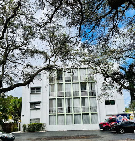 Front view of a multi-story building with vertical windows and a white facade.