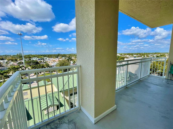 Balcony view overlooking surrounding areas with rooftops and a clear blue sky.