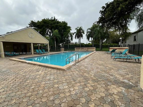 Outdoor view of a swimming pool with lounge chairs and surrounding patio area.