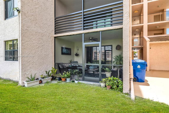 Front view of a building with a screened patio area and potted plants.