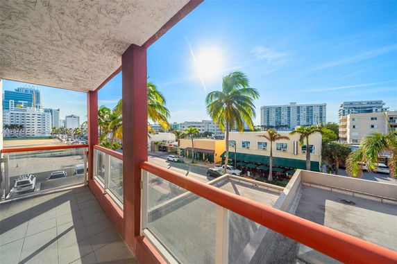 View from a balcony showing surrounding buildings and palm trees.