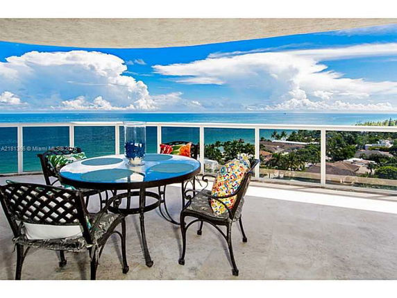 Outdoor balcony with a table and chairs overlooking a panoramic ocean view.