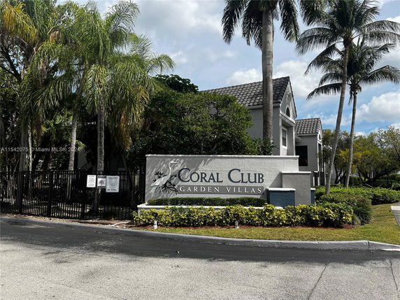 Front view of a residential community entrance sign with buildings in the background.