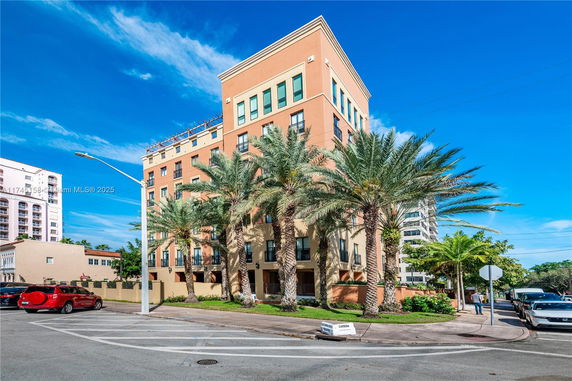 Front view of a multi-story building with palm trees in front.