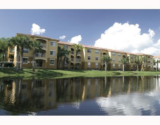 Front view of a multi-story apartment building by a water feature.
