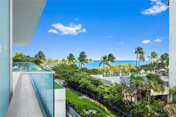 Panoramic view from a balcony overlooking the ocean and palm trees.