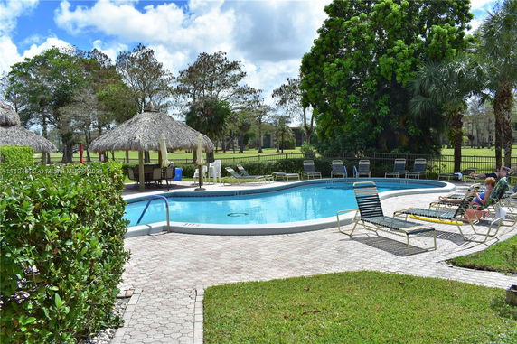 Outdoor swimming pool area with lounge chairs and thatched umbrellas.