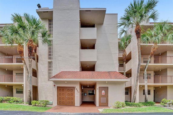 Front view of a multi-story apartment building with balconies and a red-roofed entrance.