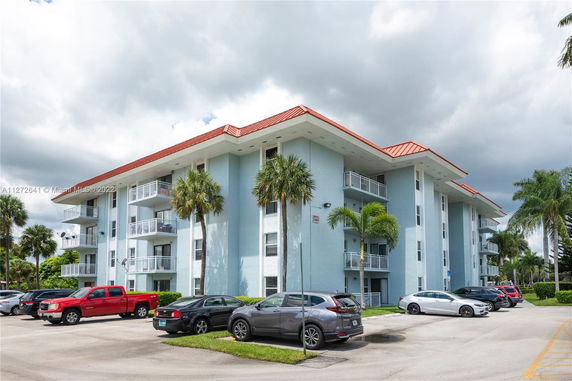 Front view of a multi-story residential building with balconies and red roof.