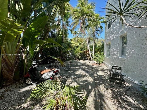 Side view of a white building with surrounding tropical plants.