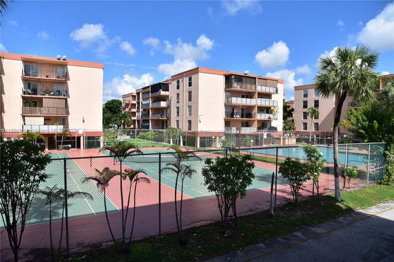 Multiple-story apartment buildings with outdoor tennis courts in front.