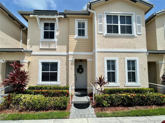 Front view of a two-story townhouse with multiple windows and a small porch entrance.