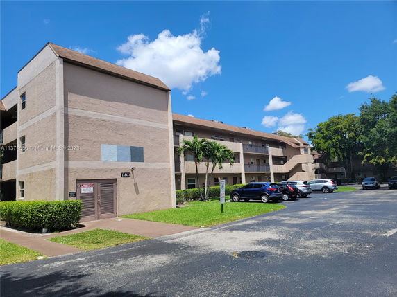 Front view of a multi-story residential building with parking area.