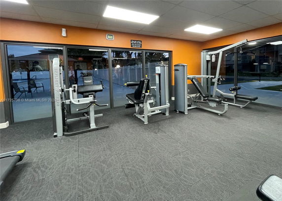 Indoor gym with exercise equipment and large windows.