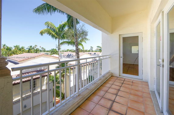 View from a balcony showing the rooftops of surrounding houses with palm trees visible.