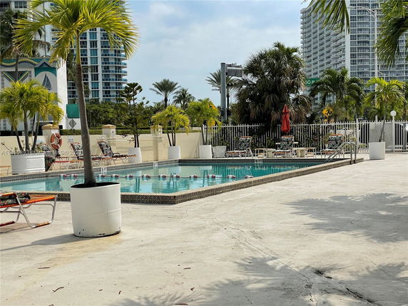 Outdoor swimming pool area with lounge chairs and potted plants.