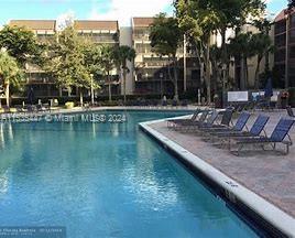 View of a pool area in front of a multi-story building with balconies.