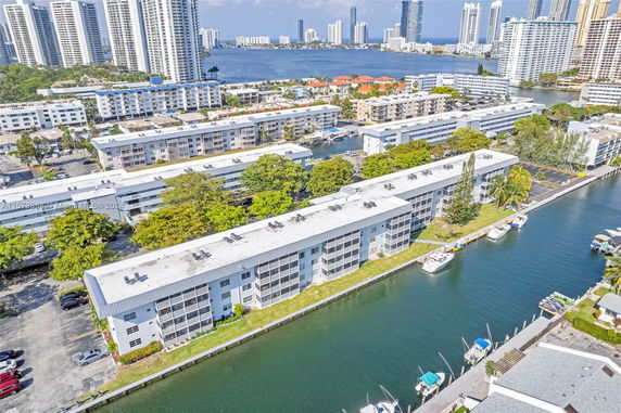 Aerial view of residential apartment complexes near a waterway, with tall buildings in the background.