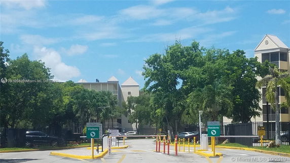 Outdoor parking area with visitor and resident signs near a residential building.