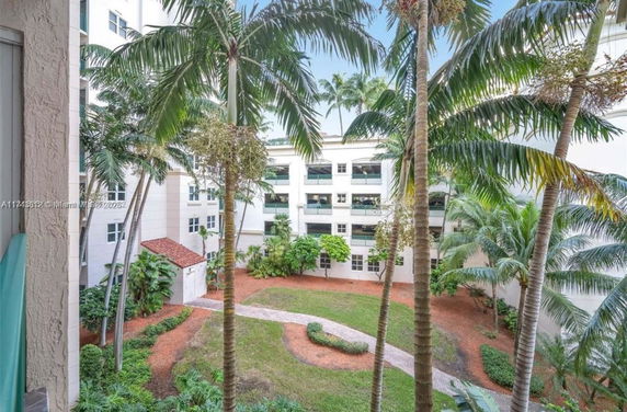View of a building courtyard with palm trees and green landscaping.