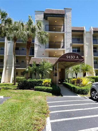 Front view of a multi-story residential building with balconies and an entrance canopy.