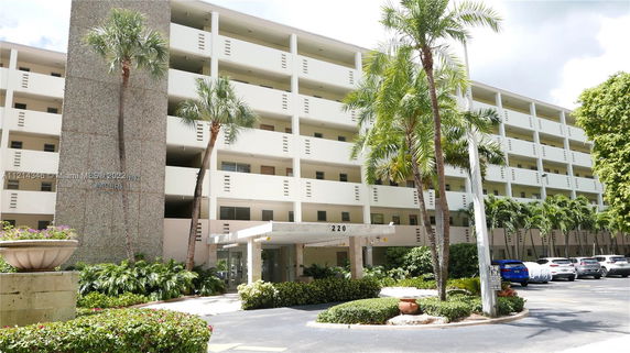 Front view of a multi-story residential building with balconies and entrance.
