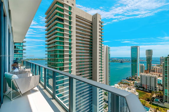 Panoramic view from a high-rise balcony showing city buildings and a water body.