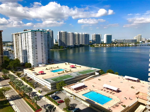Panoramic view overlooking high-rise buildings near a body of water with swimming pools on rooftops.