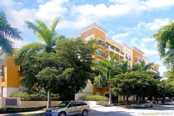 Front view of a multi-story apartment building with balconies and orange accents.