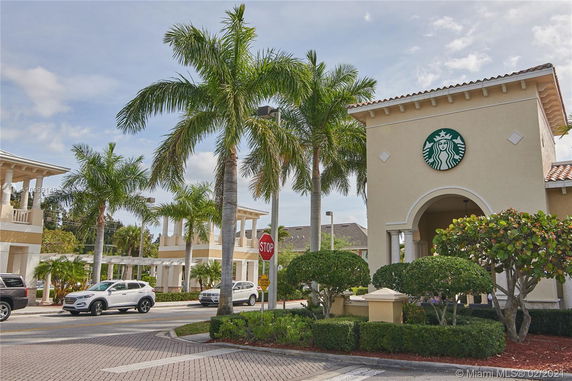 Front view of a building with a distinctive logo on it and palm trees nearby.