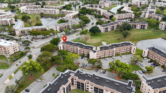 Aerial view of a residential complex with multiple multi-story buildings surrounded by greenery and roads.