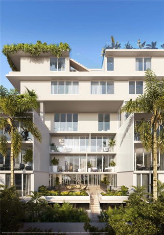 Front view of a modern multi-story building with large windows and balconies, featuring plants and greenery.