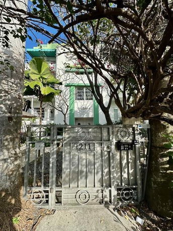 Front view of a multi-story building with a decorative gate and surrounding foliage.