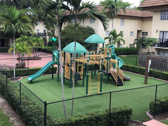 Outdoor playground with slides and climbing structures surrounded by greenery.