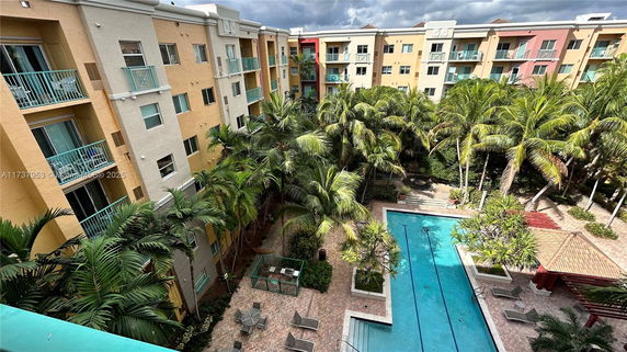Aerial view of residential building complex with a central swimming pool and surrounding palm trees.