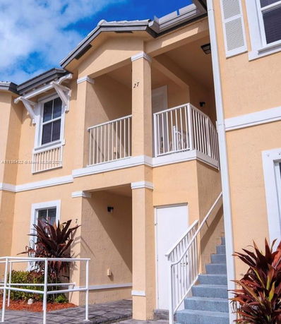 Front view of a two-story building with balconies and stairs.